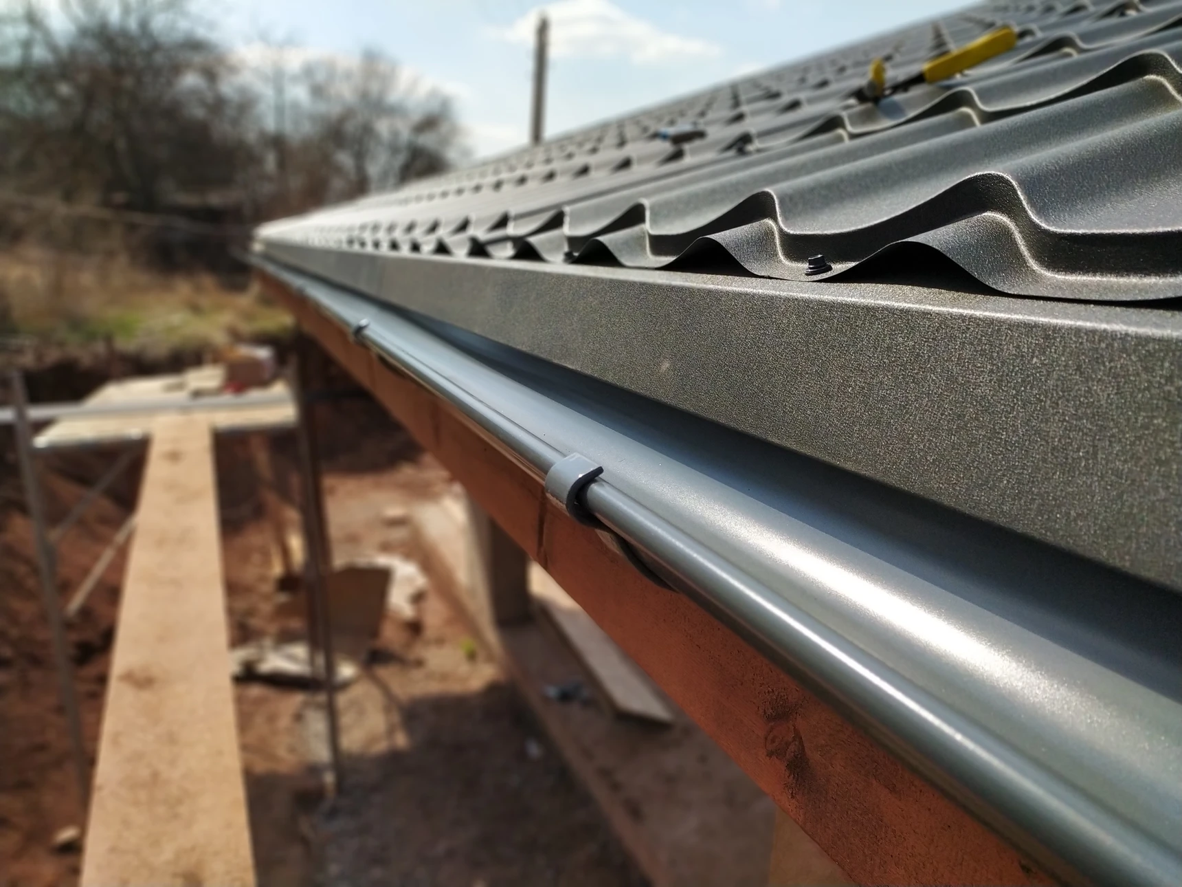Ouvrier installateur en équipement de protection sur toiture de bâtiment résidentiel, travaillant sur structure métallique de support