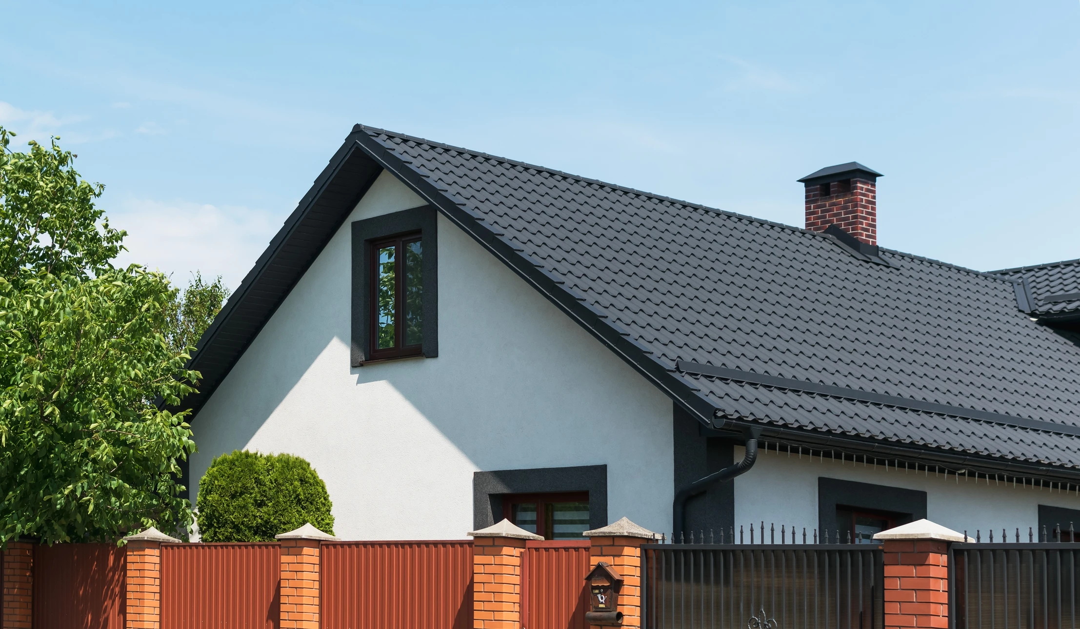 Ouvrier en équipement de sécurité installant de l'isolation thermique entre chevrons de toiture dans combles en construction