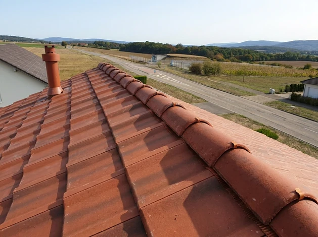 Intérieur d'un bâtiment en construction montrant la charpente en bois brut avec poutres principales et secondaires