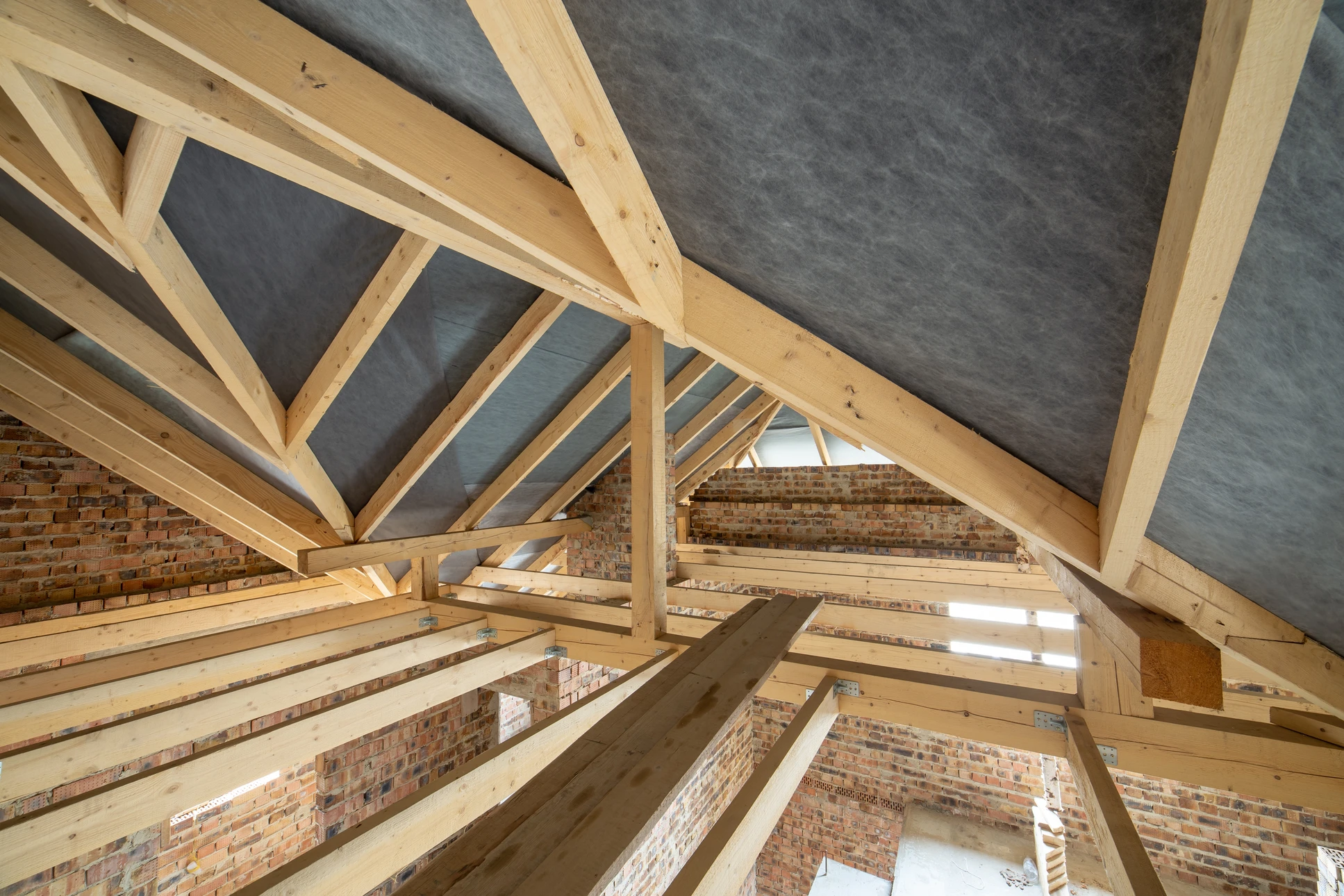 Ouvrier en équipement de protection individuelle installant de l'isolation thermique dans les combles d'une habitation